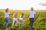 Family, summer and holiday concept - Group of women and girls going away in green field