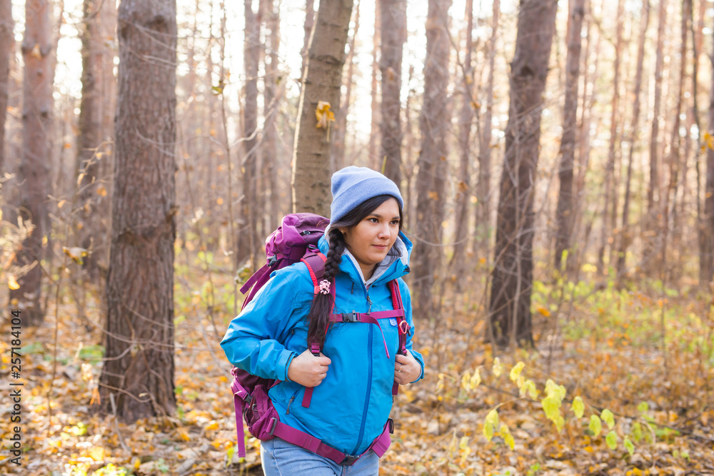 People, hike and nature concept - Female tourist walking in the autumn forest People, hike and nature concept - Female tourist walking in the autumn forest