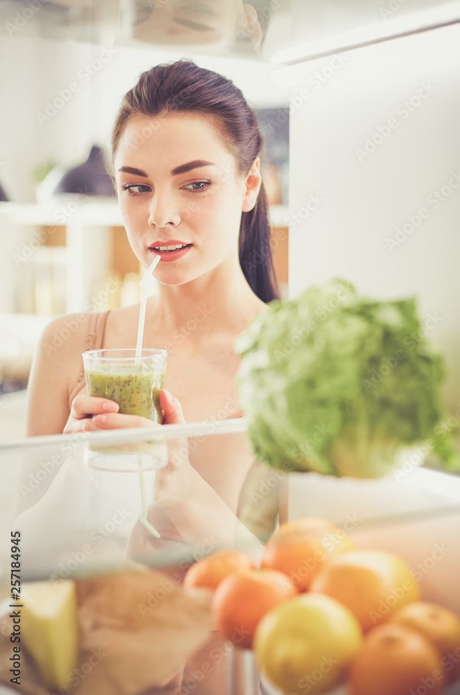Smiling woman taking a fresh vegetable out of the fridge, healthy food concept