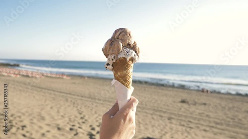 Hand holding an ice cream at the beach