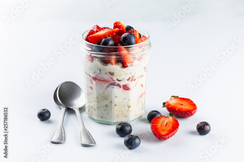 Overnight oats with chia seeds and fresh strawberries and blueberries in a glass jar. Healthy breakfast.