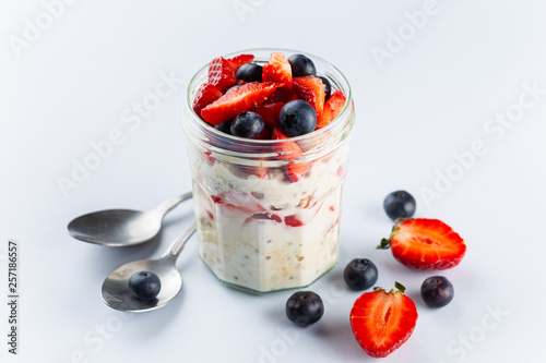 Overnight oats with chia seeds and fresh strawberries and blueberries in a glass jar. Healthy breakfast.