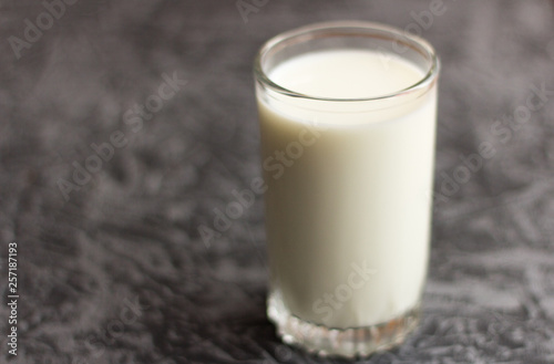 a glass of fresh cow's milk on a grey background