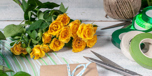 Banner. Workplace florist. Elegant yellow rose, scissors, gift wrap and other accessories on the horizontal wooden background
