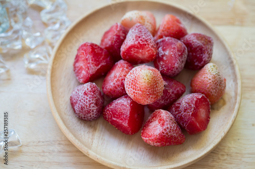 Frozen strawberries fruit on wooden plate
