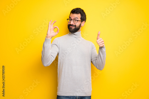 Man with beard and turtleneck showing ok sign with and giving a thumb up gesture