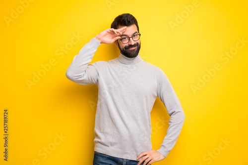 Man with beard and turtleneck saluting with hand
