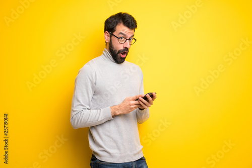 Man with beard and turtleneck surprised and sending a message © luismolinero