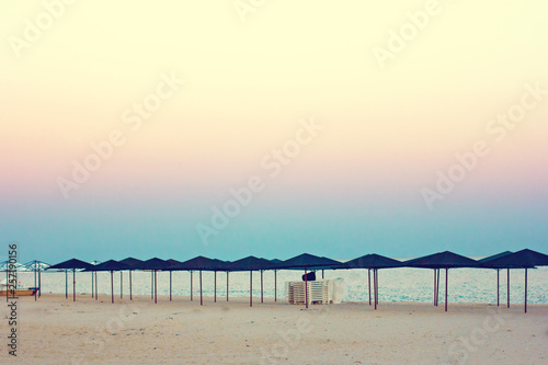 Empty beach  beach umbrellas and beautiful sunset. Romantic atmosphere.