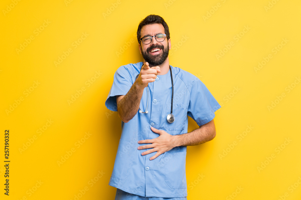 Surgeon doctor man pointing with finger at someone and laughing a lot Surgeon doctor man pointing with finger at someone and laughing a lot