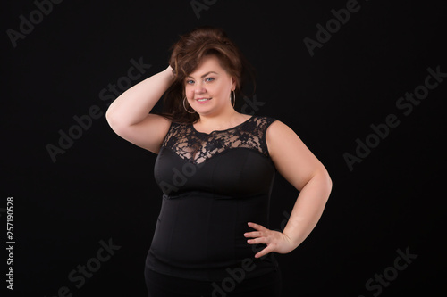Beautiful buxom girl in a black evening dress. Portrait of a chubby girl with high hairstyle and evening make-up
