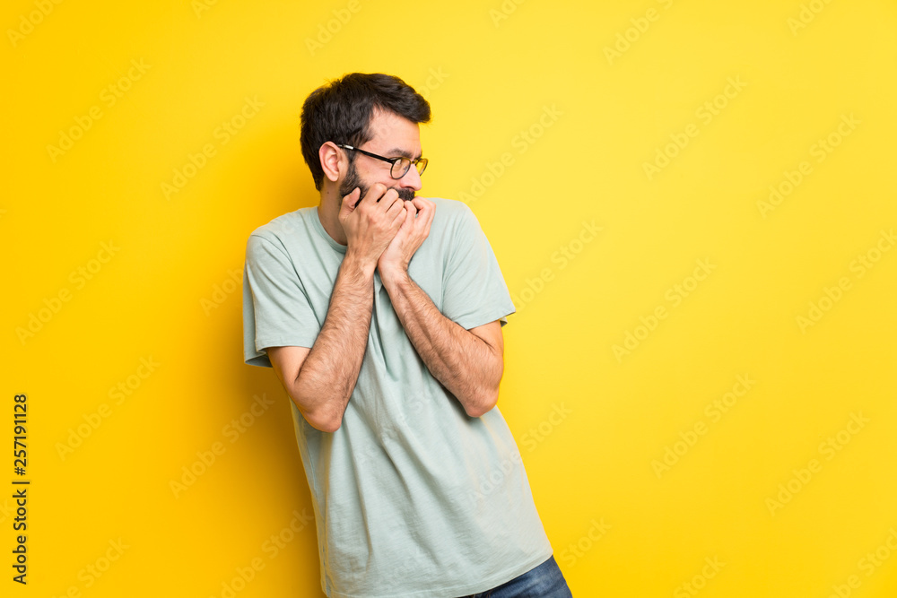 Man with beard and green shirt is a little bit nervous and scared putting hands to mouth Man with beard and green shirt is a little bit nervous and scared putting hands to mouth