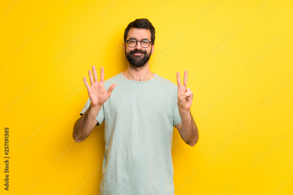 Man with beard and green shirt counting seven with fingers Man with beard and green shirt counting seven with fingers