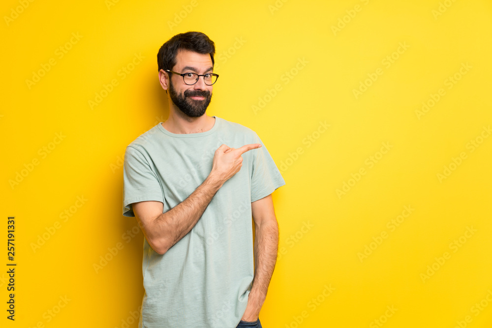 Man with beard and green shirt pointing to the side to present a product Man with beard and green shirt pointing to the side to present a product