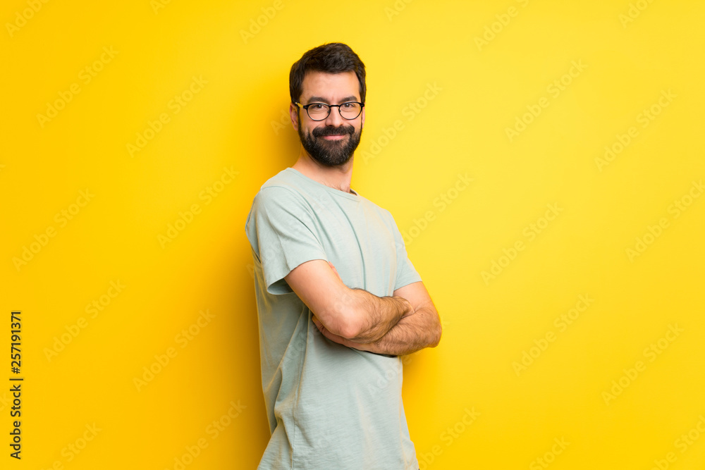 Man with beard and green shirt with arms crossed and looking forward
