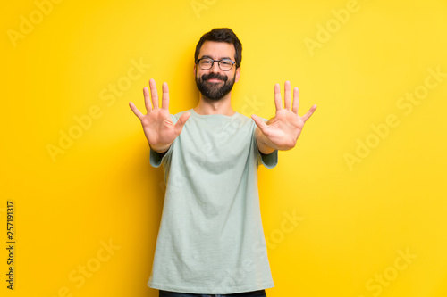 Man with beard and green shirt counting ten with fingers