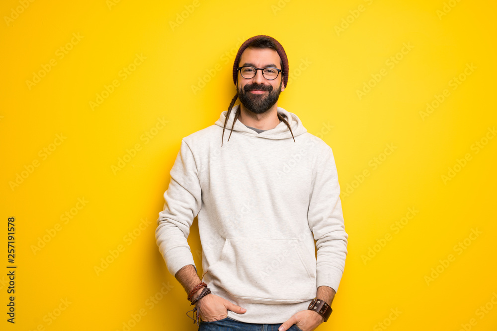 Hippie man with dreadlocks posing with arms at hip and laughing looking to the front