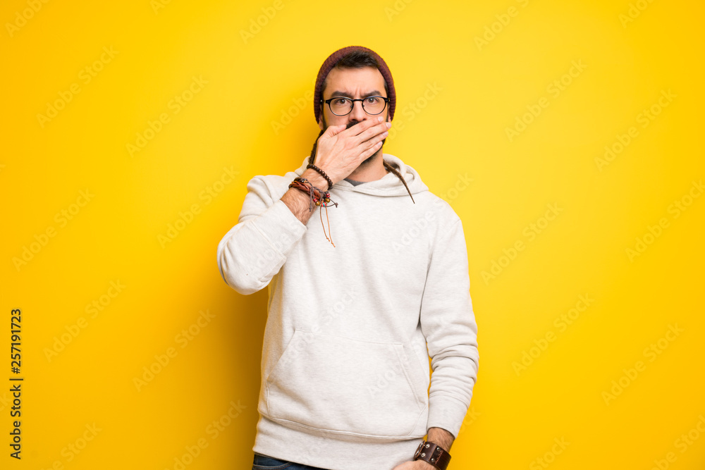Hippie man with dreadlocks covering mouth with hands for saying something inappropriate Hippie man with dreadlocks covering mouth with hands for saying something inappropriate
