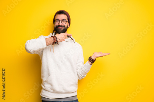Hippie man with dreadlocks holding copyspace imaginary on the palm to insert an ad