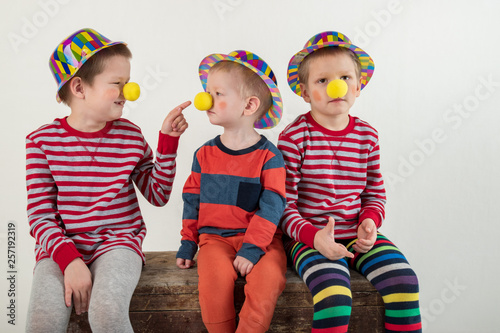 Funny clown children dressed up in costumes and represent the circus. The child is playing at home. hat is bowler and a yellow patch on the nose. 1 April. concept of a fool's day. Copy space.