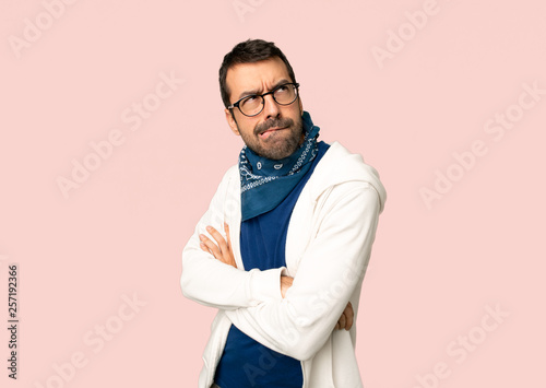 Handsome man with glasses with confuse face expression while bites lip on isolated pink background © luismolinero