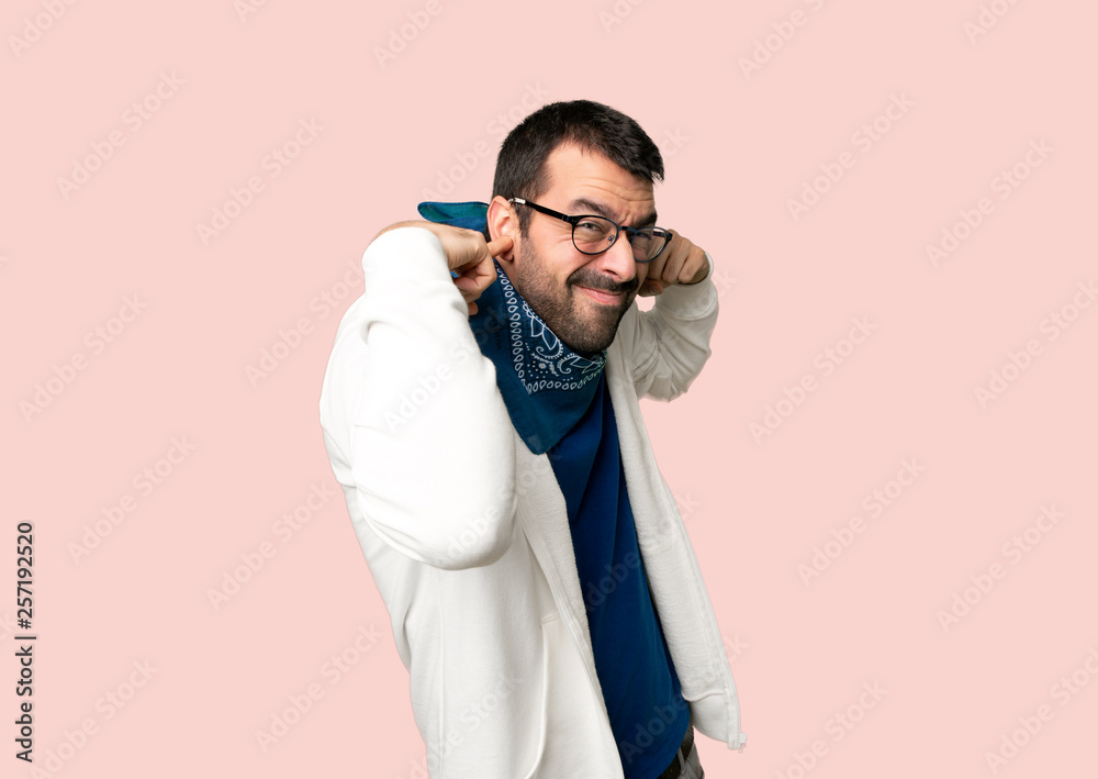 Handsome man with glasses covering both ears with hands on isolated pink background Handsome man with glasses covering both ears with hands on isolated pink background