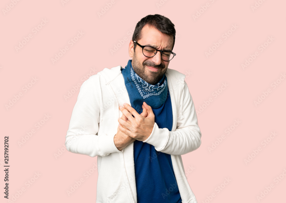 Handsome man with glasses having a pain in the heart on isolated pink background Handsome man with glasses having a pain in the heart on isolated pink background