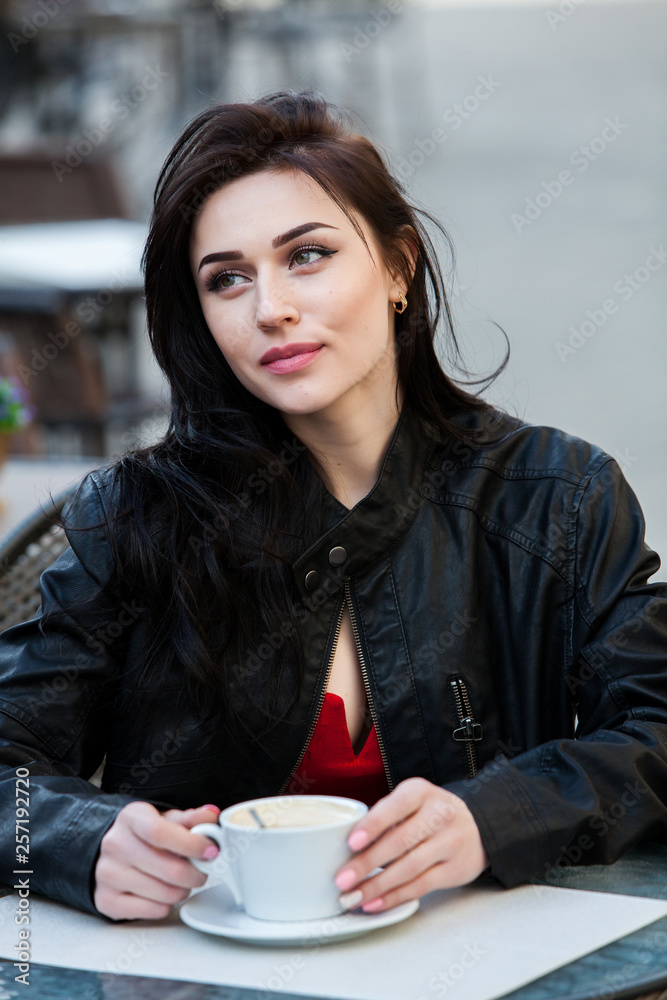 Gorgeous young woman with cup of coffee in city street. Coffee break. Stylish hipster girl drinking coffee in street. Outdoors fashion portrait of young beautiful girl drinking coffee. Gorgeous young woman with cup of coffee in city street. Coffee break. Stylish hipster girl drinking coffee in street. Outdoors fashion portrait of young beautiful girl drinking coffee.