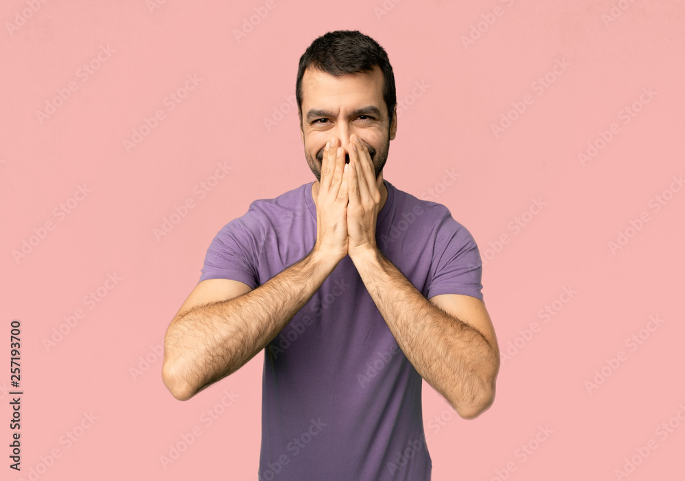 Handsome man smiling a lot while covering mouth on isolated pink background Handsome man smiling a lot while covering mouth on isolated pink background
