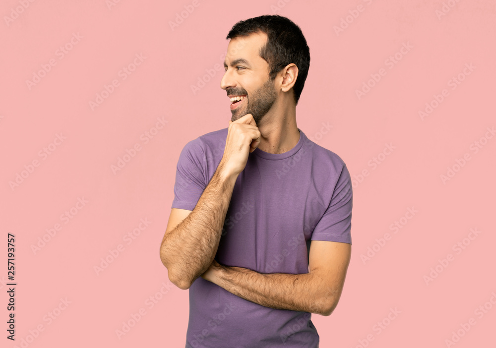Handsome man looking to the side with the hand on the chin on isolated pink background Handsome man looking to the side with the hand on the chin on isolated pink background