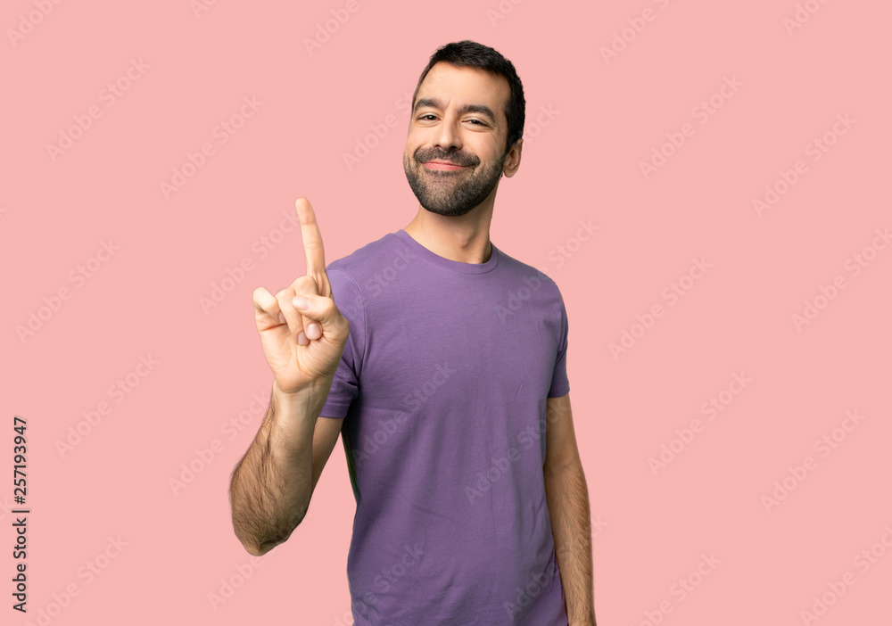 Handsome man showing and lifting a finger in sign of the best on isolated pink background Handsome man showing and lifting a finger in sign of the best on isolated pink background