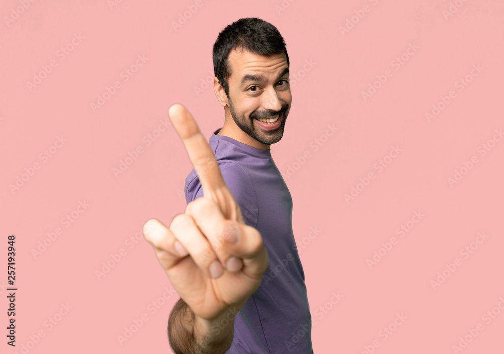 Handsome man showing and lifting a finger on isolated pink background Handsome man showing and lifting a finger on isolated pink background