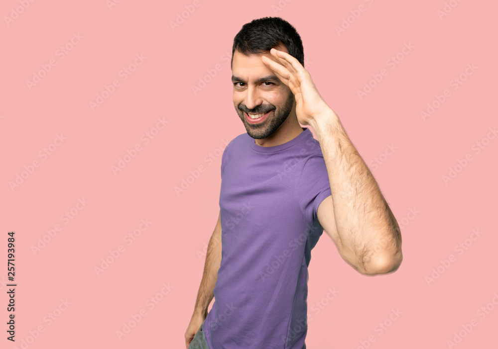 Handsome man saluting with hand on isolated pink background Handsome man saluting with hand on isolated pink background