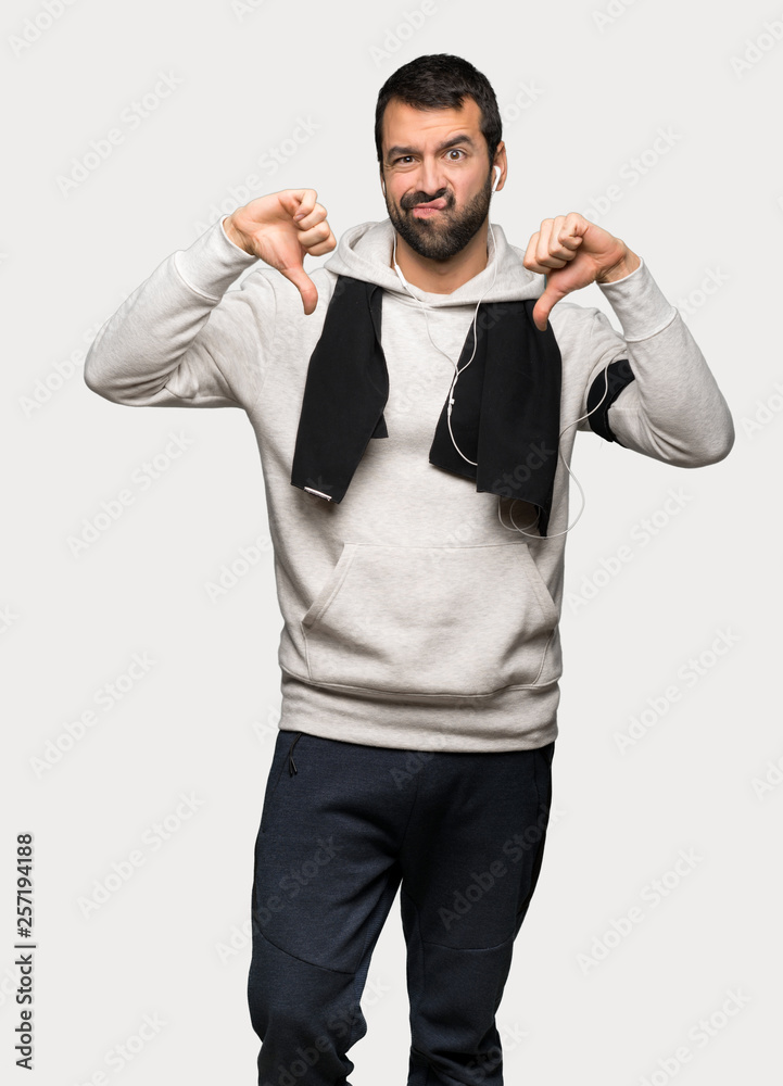 Sport man showing thumb down with both hands over isolated grey background Sport man showing thumb down with both hands over isolated grey background