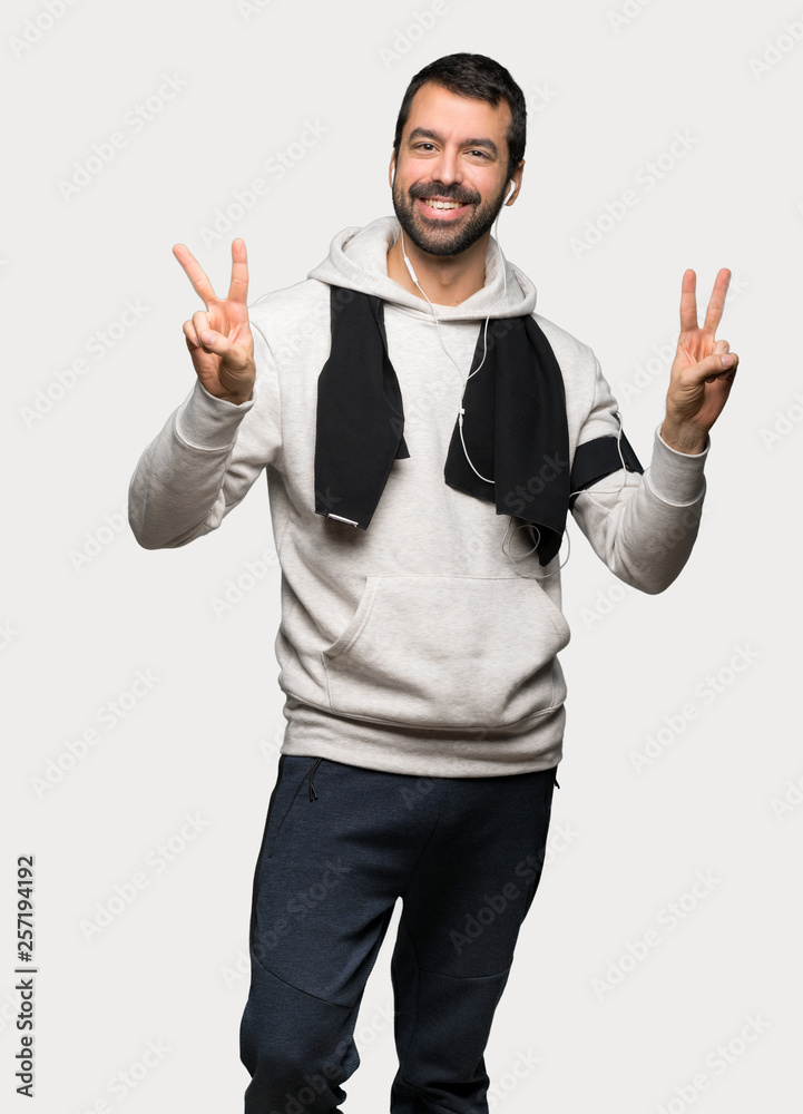 Sport man smiling and showing victory sign with both hands over isolated grey background Sport man smiling and showing victory sign with both hands over isolated grey background