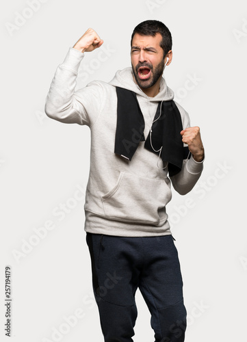 Sport man celebrating a victory over isolated grey background