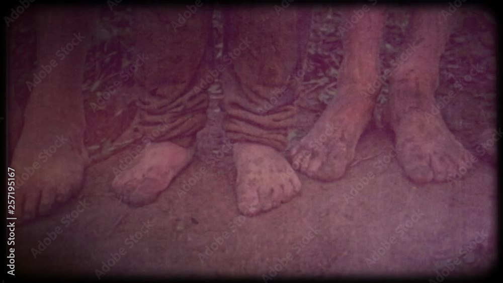 Family video archive. Retro camera 8 mm. Old film. Vintage. Baby bare feet Close-up barefooted dirty feet of a children standing on a damp ground. 
