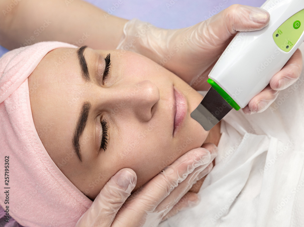 Fototapeta premium Woman receiving cleansing therapy with professional ultrasonic equipment in beauty salon. Face Skin Care.