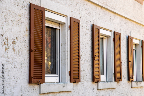 House facade with two windows with old wooden shutters with slats