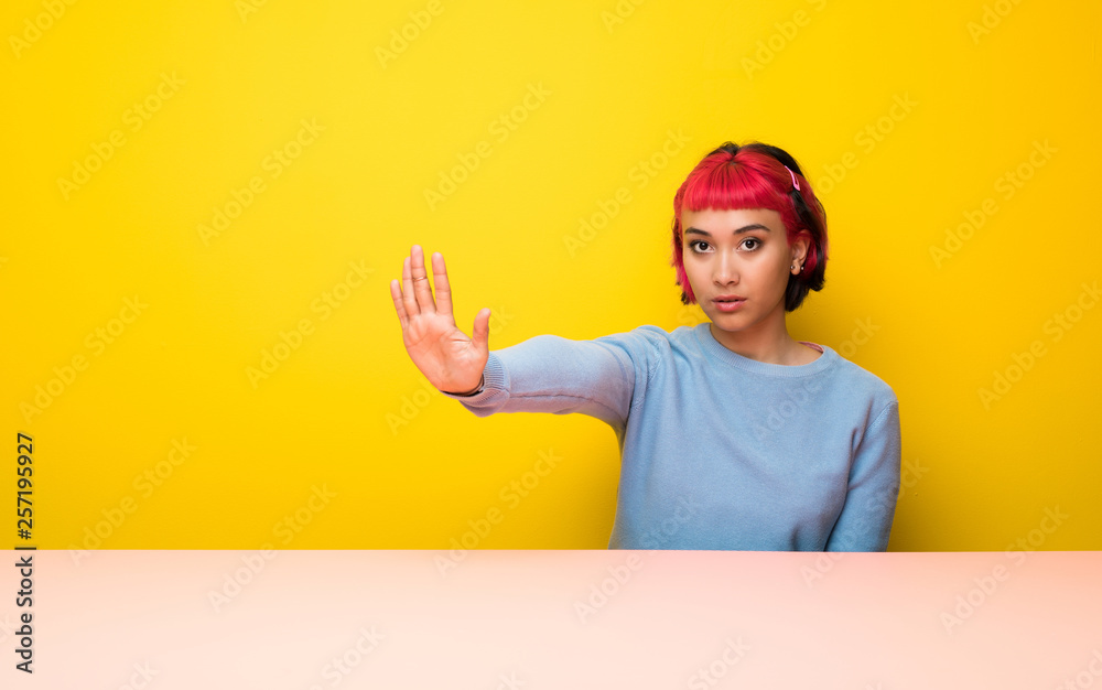 Young woman with pink hair making stop gesture and disappointed