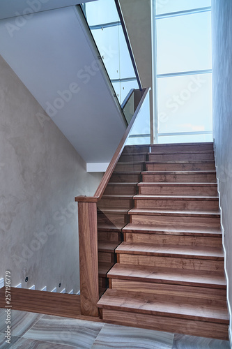 Part of wooden steps with glass railings. Walnut staircase
