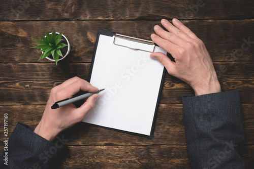 Signing of business contract or agreement mock up. To do list with copy space. Blank paper page in a businessman hands on office table background.