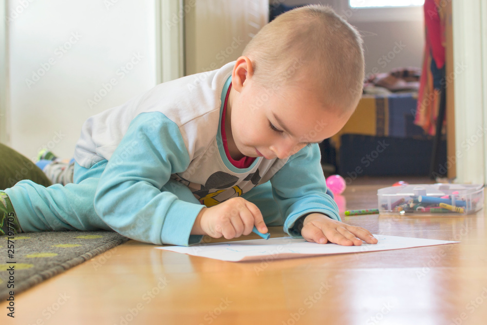Cute little kid boy drawing a story with colorful pens at home. Cute little kid boy drawing a story with colorful pens at home.
