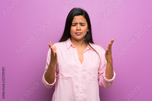 Young Colombian girl over purple wall frustrated by a bad situation