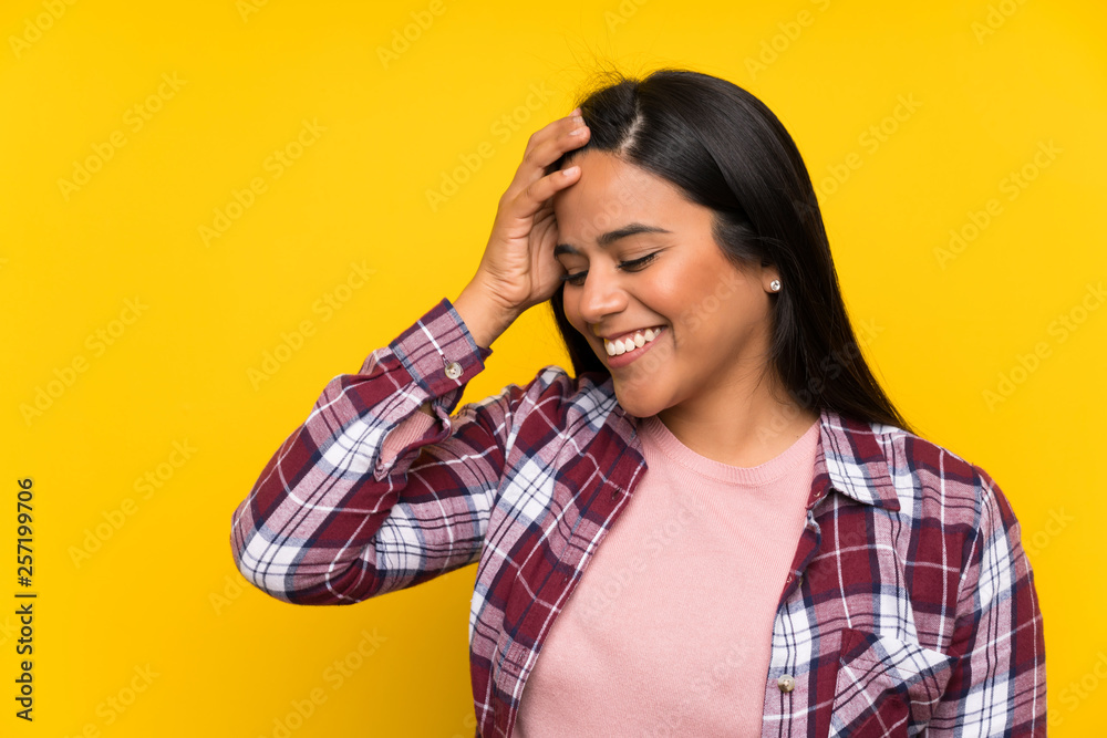 Young Colombian girl over yellow wall laughing Young Colombian girl over yellow wall laughing