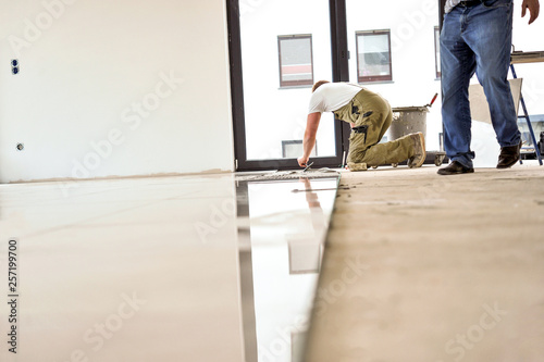 Fotografie Handwerker arbeiten in einem Neubau, verlegen Fliesen – selektive Schärfe, viel