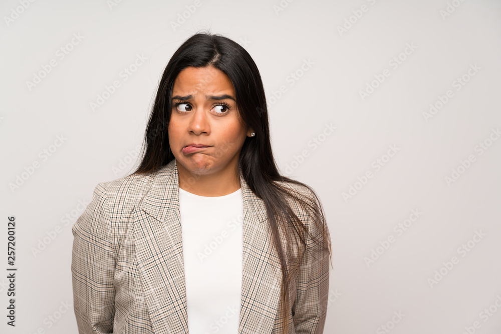 Young Colombian girl over white wall having doubts and with confuse face expression Young Colombian girl over white wall having doubts and with confuse face expression