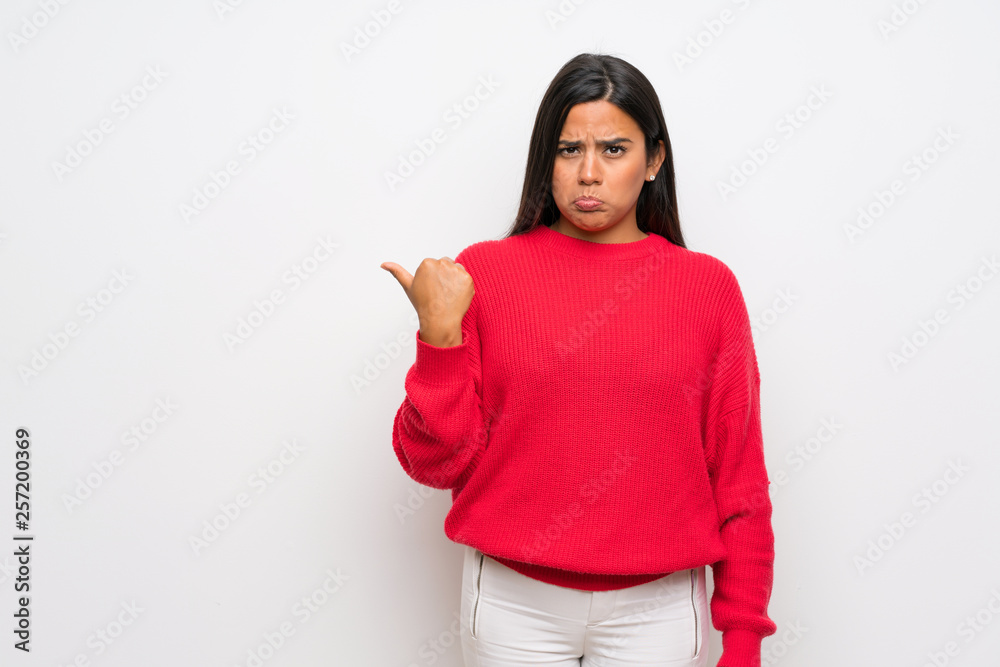 Young Colombian girl with red sweater unhappy and pointing to the side Young Colombian girl with red sweater unhappy and pointing to the side