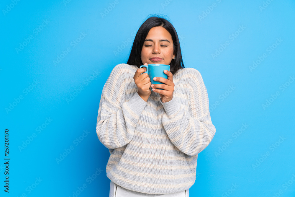 Young Colombian girl with sweater holding a hot cup of coffee Young Colombian girl with sweater holding a hot cup of coffee