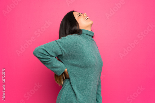 Young Colombian girl with green sweater suffering from backache for having made an effort photo